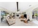 Open living room featuring fireplace, ceiling fan, skylight, and sliding glass doors to an enclosed lanai at 18584 Alphonse Cir, Port Charlotte, FL 33948