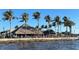 Charming waterfront restaurant featuring thatched roofs, palm trees, and vibrant, colorful seating at 18584 Alphonse Cir, Port Charlotte, FL 33948