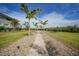 Scenic backyard with a charming stone path and tall palm trees, offering a tranquil walk to the waterfront at 19023 Midway Blvd, Port Charlotte, FL 33948