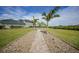 Lush backyard featuring a paver path, well-manicured lawn, and tropical palm trees leading to the waterfront at 19023 Midway Blvd, Port Charlotte, FL 33948