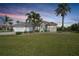 A single-story home with a beautiful lawn, palm trees, and a colorful blue front door at 19023 Midway Blvd, Port Charlotte, FL 33948