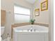 Bathroom with a large corner tub near a window, a toilet, and neutral decor at 235 Tournament Rd, Rotonda West, FL 33947