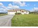 Well-maintained one-story home featuring an attached garage and lush green lawn at 235 Tournament Rd, Rotonda West, FL 33947
