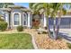 A covered front entry and beautiful landscaping lead to a decorative glass front door and welcoming entrance at 24260 Westgate Blvd, Port Charlotte, FL 33980