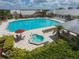 A resort-style pool and spa area surrounded by lounge chairs, umbrellas, and lush landscaping on a sunny day at 24260 Westgate Blvd, Port Charlotte, FL 33980