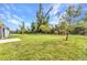 Expansive backyard featuring lush lawn and mature trees under a bright blue sky at 25340 E Lenox Cir, Punta Gorda, FL 33950