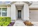 Inviting front entrance featuring a covered porch with a modern gray door and manicured bushes at 25340 E Lenox Cir, Punta Gorda, FL 33950