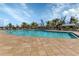 Community pool with ample lounge seating, mature landscaping, and a shaded seating area at 25340 E Lenox Cir, Punta Gorda, FL 33950