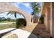 A close up of an arched walkway entrance to the home showcasing lush greenery and gravel landscaping at 2621 Via Veneto Dr, Punta Gorda, FL 33950