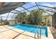 A pool with a metal ladder is surrounded by a screened enclosure and tropical landscaping at 2621 Via Veneto Dr, Punta Gorda, FL 33950