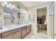 Elegant bathroom featuring dual sinks, a spacious vanity, and an adjacent walk-in closet for ample storage space at 264 Soliera St, Nokomis, FL 34275