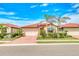 Charming single-story home featuring a red tile roof, lush landscaping, and a brick driveway, all under a bright blue sky at 264 Soliera St, Nokomis, FL 34275