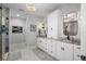 Modern bathroom featuring double vanities, granite countertops, decorative mirrors, and a glass enclosed shower at 310 Severin Se Rd, Port Charlotte, FL 33952