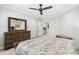 Calm bedroom features a bed with patterned bedding, wooden dresser, ceiling fan, and neutral walls at 310 Severin Se Rd, Port Charlotte, FL 33952