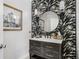 Stylish half bath featuring a dark vanity, round mirror, and black and white patterned wallpaper at 310 Severin Se Rd, Port Charlotte, FL 33952