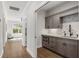 Hallway view of a sleek kitchenette area with gray cabinets, marble backsplash, and stainless steel microwave at 310 Severin Se Rd, Port Charlotte, FL 33952