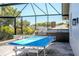 A well-equipped outdoor kitchen and entertaining area located in a screened lanai with a blue ping pong table at 310 Severin Se Rd, Port Charlotte, FL 33952