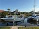 Boats on boat lifts on a waterfront property with a clear blue sky and palm trees in the background at 3414 Sandpiper Dr, Punta Gorda, FL 33950