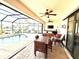 Enclosed patio with ceiling fans, outdoor dining set, and a sparkling pool overlooking the landscaped backyard at 3414 Sandpiper Dr, Punta Gorda, FL 33950