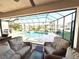 A screened-in outdoor living space with comfortable seating overlooks a private pool and lush landscaping at 3414 Sandpiper Dr, Punta Gorda, FL 33950