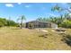A screened pool area sits near a home with a yard featuring mature trees and landscaping at 4053 Joseph St, Port Charlotte, FL 33948