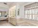 Bright bathroom features a tiled vanity, soaking tub with floral curtains, and ensuite bedroom access at 4053 Joseph St, Port Charlotte, FL 33948
