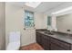 Bathroom featuring a toilet, vanity with dark wood cabinets and mirror, and a window for natural light at 4438 Meager Cir, Port Charlotte, FL 33948
