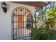 Inviting front entry with an arched gate, textured stucco, and tropical plants enhancing the home's curb appeal at 4438 Meager Cir, Port Charlotte, FL 33948
