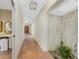 Hallway features terra cotta tile floors, an arched entry, unique wall decor, and ample lighting at 4438 Meager Cir, Port Charlotte, FL 33948