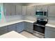 Well-appointed kitchen featuring gray cabinets, stainless steel appliances, subway tile, and quartz countertops at 5342 Wagon Wheel Dr, North Port, FL 34291