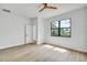 A bright bedroom with wood-look floors, a ceiling fan, and a window overlooking trees at 551 Crandall Nw St, Port Charlotte, FL 33952