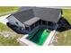 Aerial view showcasing a home with a dark roof, covered patio, and an in-ground pool in need of maintenance at 5705 44Th E Ave, Bradenton, FL 34203