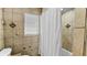 Cozy bathroom featuring textured tile walls, window with blinds, and a shower with a white curtain at 5705 44Th E Ave, Bradenton, FL 34203