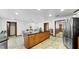 Open-concept kitchen featuring a large island with counter seating, tile flooring, and seamless flow to dining area and stainless appliances at 5705 44Th E Ave, Bradenton, FL 34203