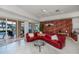 Bright living room featuring a red leather sofa, tile floors, and sliding glass doors to the pool area at 5733 White Jasmine Way, North Port, FL 34287