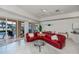 Bright living room featuring a red leather sofa, tile floors, and sliding glass doors to the pool area at 5733 White Jasmine Way, North Port, FL 34287