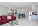 Open-concept living space with a red sofa, tile flooring, and a breakfast bar area overlooking the kitchen at 5733 White Jasmine Way, North Port, FL 34287