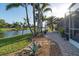 The backyard offers a relaxing space with its waterside view, lush trees, and a walkway to the patio at 1091 Rotonda Cir, Rotonda West, FL 33947