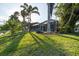 Backyard showcasing lush green grass, palm trees, and a spacious screened-in patio at 1091 Rotonda Cir, Rotonda West, FL 33947