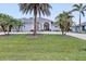 Inviting single-Gathering home featuring a beautifully landscaped front yard and a charming blue exterior with palm trees at 1091 Rotonda Cir, Rotonda West, FL 33947
