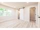 Bright bedroom with white walls, wood-look floors, barn door, and walk-in closet at 1357 Nimrod St, Port Charlotte, FL 33952