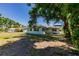 Single story home with many windows surrounded by a green lawn and large trees in a residential neighborhood at 1357 Nimrod St, Port Charlotte, FL 33952