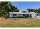 View of a single-story home with mature trees, well-kept lawn, and stone accents on the exterior at 1357 Nimrod St, Port Charlotte, FL 33952