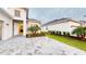 Rear view of home with paver driveway, detached garage, and tropical landscaping at 17420 Jadestone Ct, Venice, FL 34293