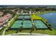 Aerial view of well-maintained tennis courts nestled in a lush community with beautiful landscaping and a serene lake at 17420 Jadestone Ct, Venice, FL 34293