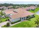 Areal view of a single-story home with a tiled roof, well-manicured lawn, and a pond view at 1940 Scarlett Ave, North Port, FL 34289