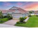 Beautiful single-story home with a well-manicured lawn, tiled roof, and a paved driveway under a colorful sky at 1940 Scarlett Ave, North Port, FL 34289