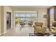 Bright living room features tile floors, an armchair, and sliding glass doors to the lanai with beautiful lake views at 1940 Scarlett Ave, North Port, FL 34289