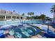 Community pool and hot tub with lounge chairs, umbrellas, and beautifully landscaped green areas at 1940 Scarlett Ave, North Port, FL 34289