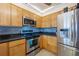 Well-lit kitchen includes wooden cabinets, stainless steel appliances, granite countertops, and modern tile backsplash at 23465 Harborview Rd # 915, Punta Gorda, FL 33980